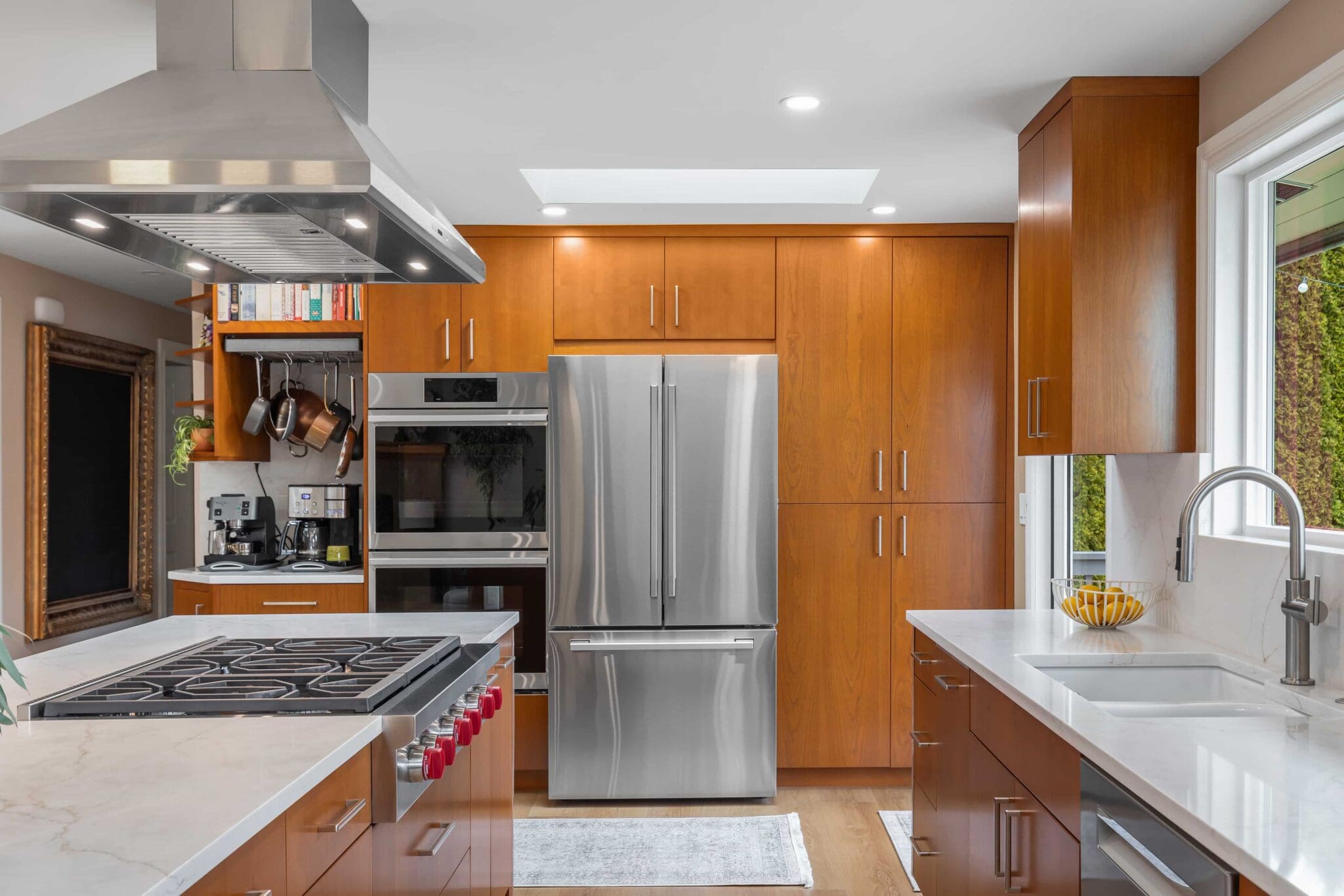 11114-34th-Pl-SW-Seattle-WA_0003-scaled Modern Black Walnut Kitchen with wood cabinets, stainless steel appliances, gas cooktop island, built-in oven, double-door fridge, window-side sink, and a bowl of bananas. Bright and clean with ample lighting.